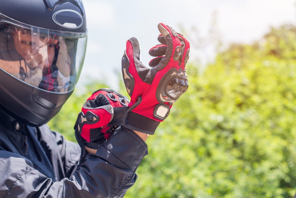 Man in a Motorcycle helmet putting on riding glove 