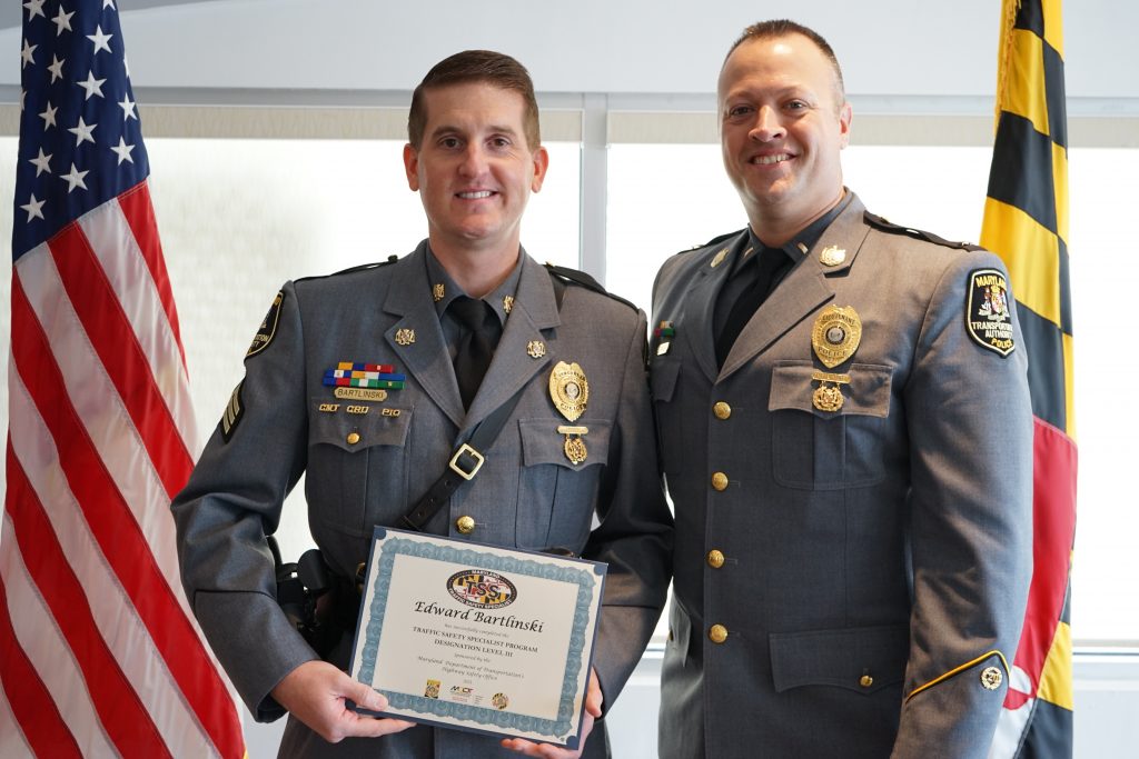 Sergeant Edward Bartlinski stands to the left with his award. Acting MDTA Police Chief Joseph F. Scott stands to his right.